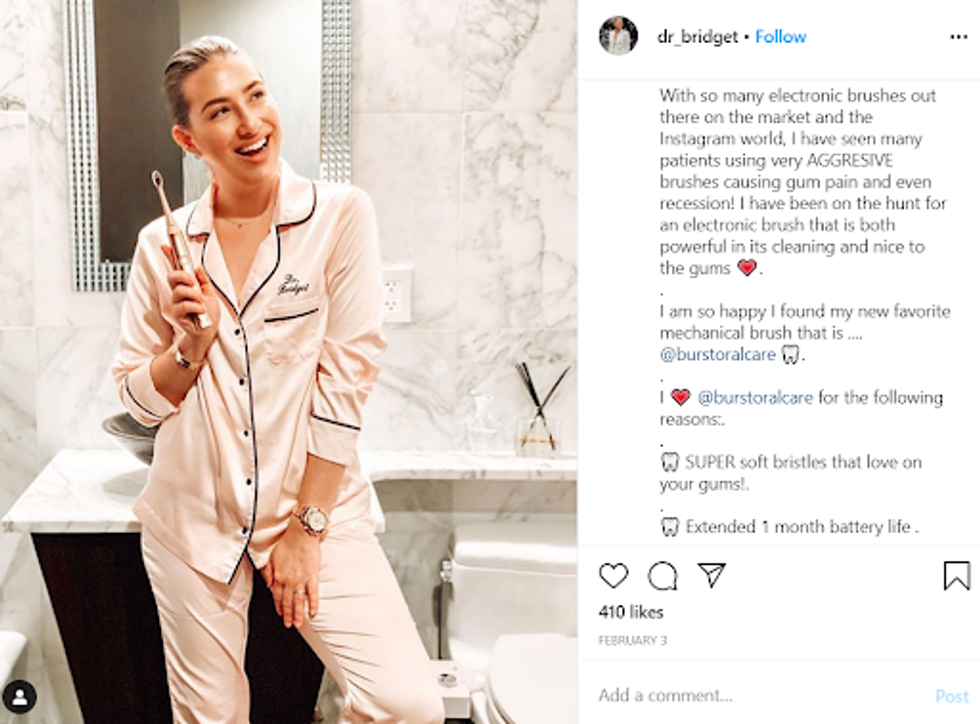 woman in pink pajamas holding a pink toothbrush